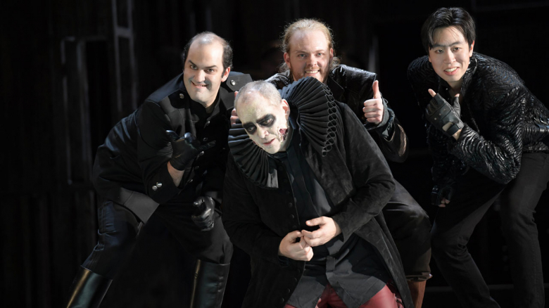 Theo Lebow (Borsa), Christopher Maltman (Rigoletto; kniend), Iain MacNeil (Marullo), Pilgoo Kang (Graf von Ceprano)